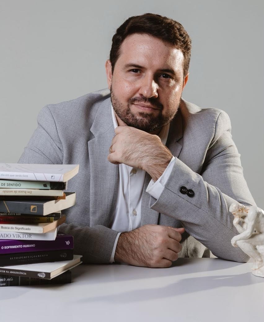 Lucas Cartaxo em estúdio, com livros de logoterapia e a figura do Pensador